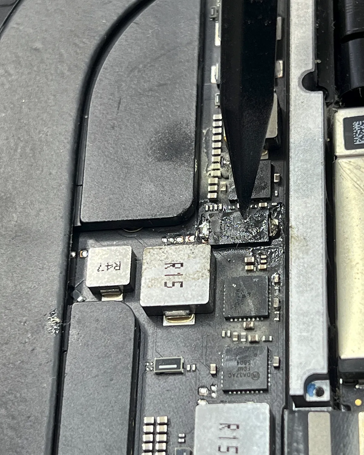 Placa de MacBook con corrosión en la zona de alimentación