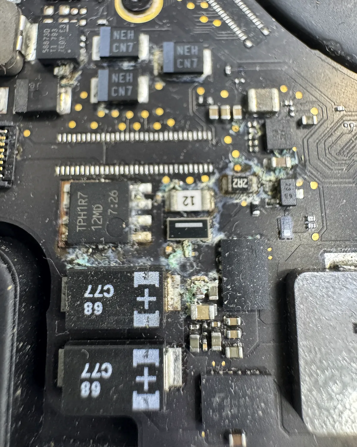 Placa de MacBook con corrosión junto a las bobinas