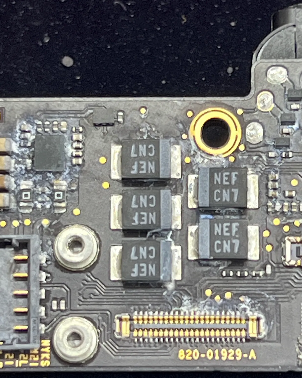 Placa lógica de MacBook con corrosión junto a un conector