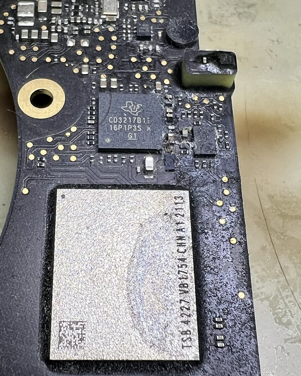 Placa de MacBook con corrosión junto al chip de memoria