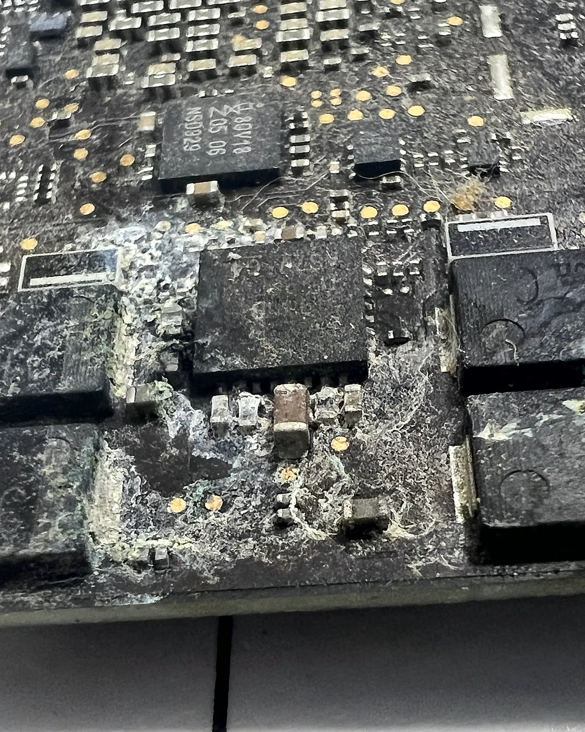 Placa de MacBook con corrosión severa tras un derrame